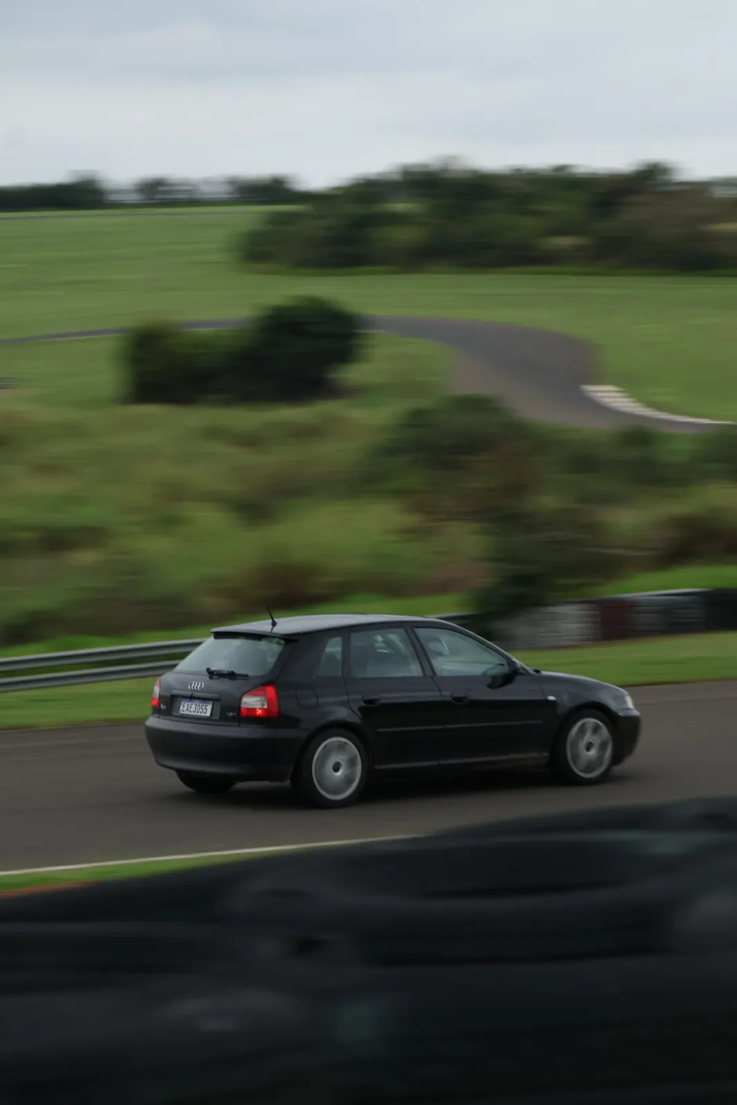 Traseira do Audi A3 preto em movimento na pista