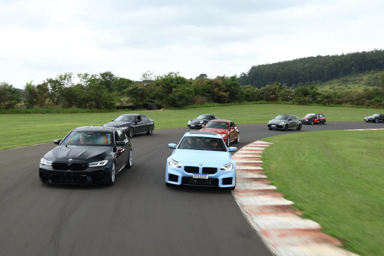 BMW M5 e BMW M2 azul liderando o pelotão na curva