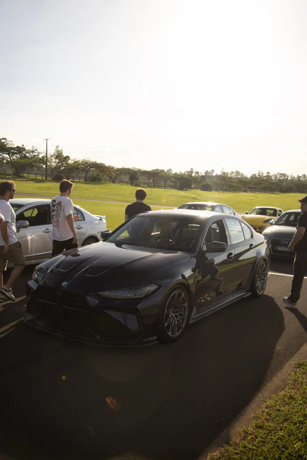 BMW M3 preto cercado por participantes