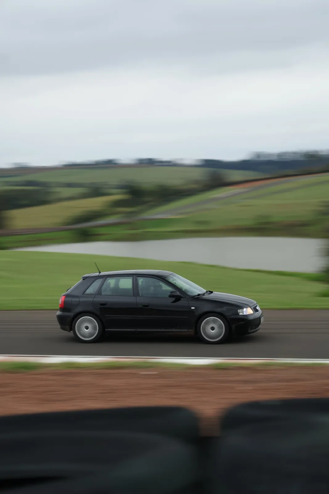 Audi A3 preto em velocidade com o lago ao fundo