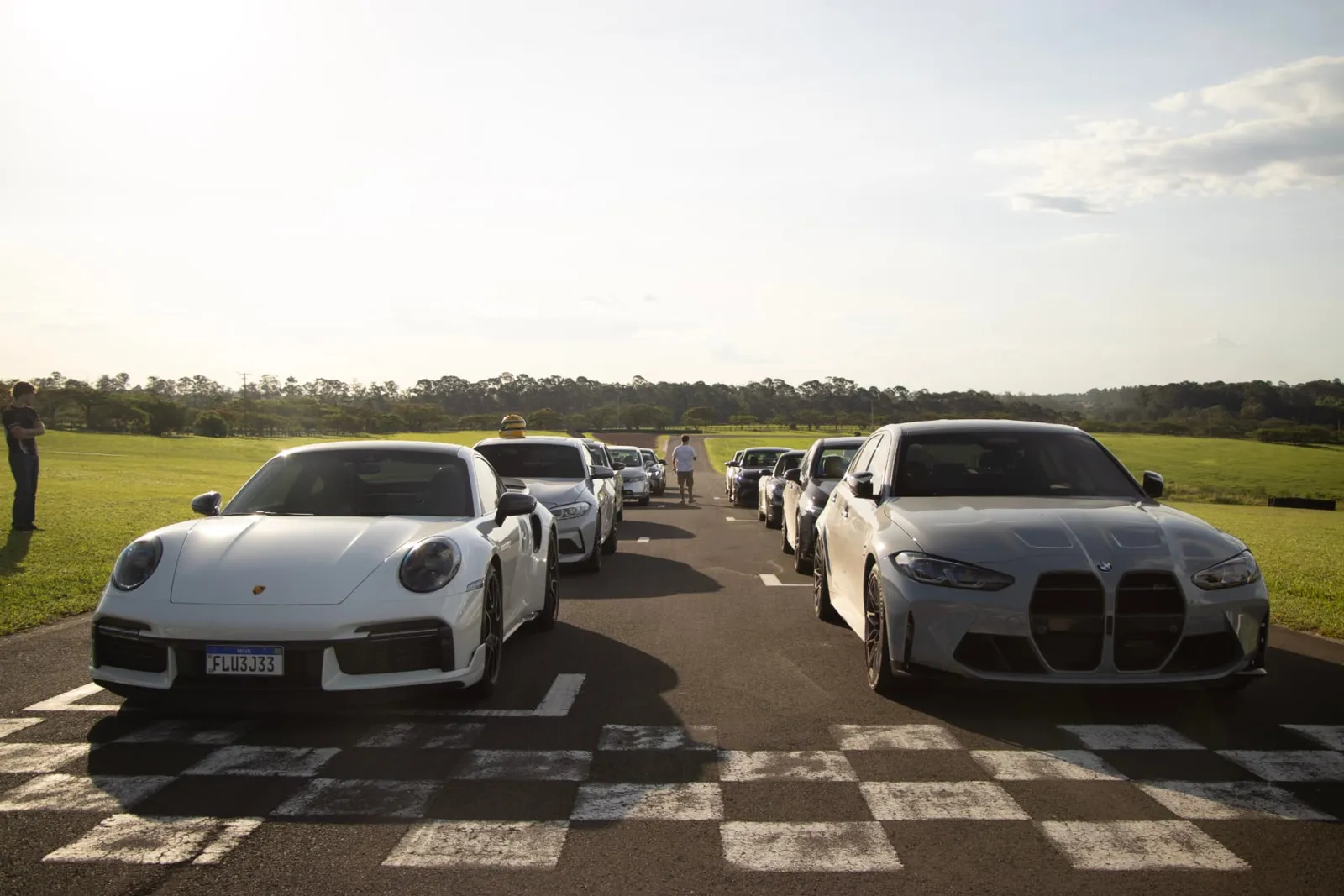 Grid de largada com Porsche 911 e BMW M3 sobre a faixa quadriculada