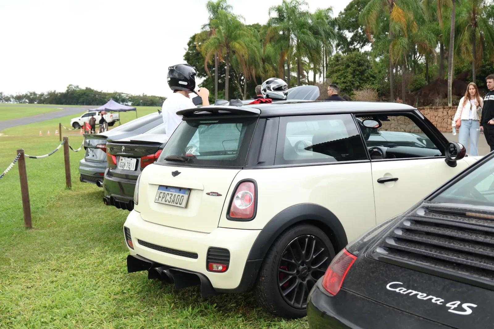 Mini John Cooper Works, BMW e Porsche Carrera 4S estacionados à beira da pista