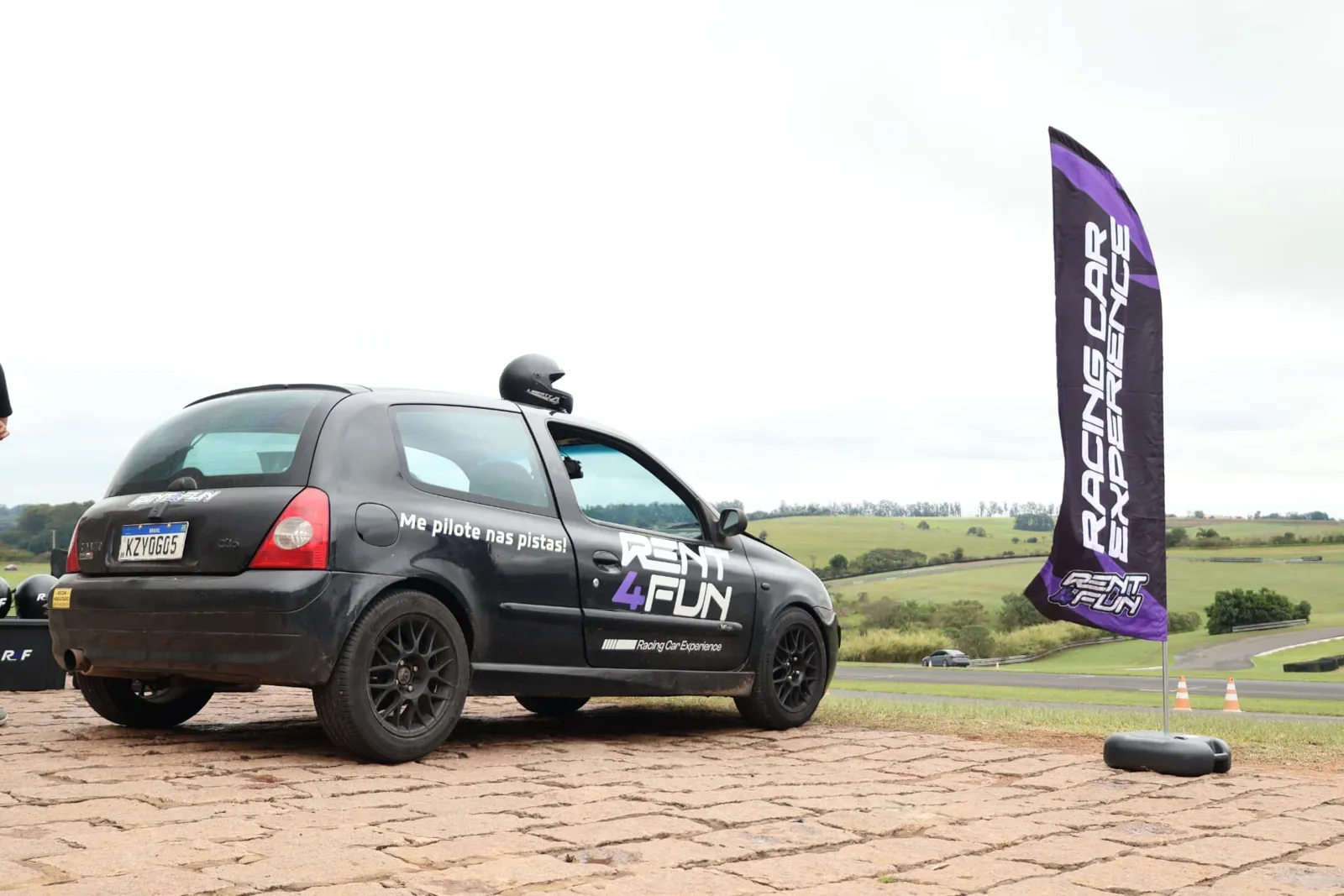 Renault Clio Rent4Fun ao lado da bandeira Racing Car Experience