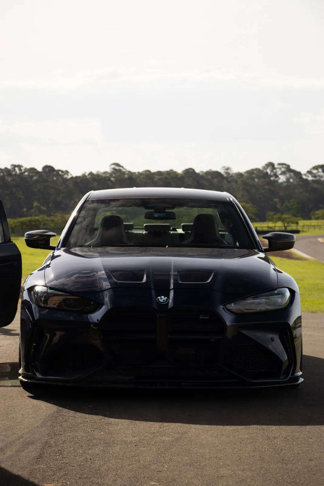 BMW M3 preto de frente no paddock