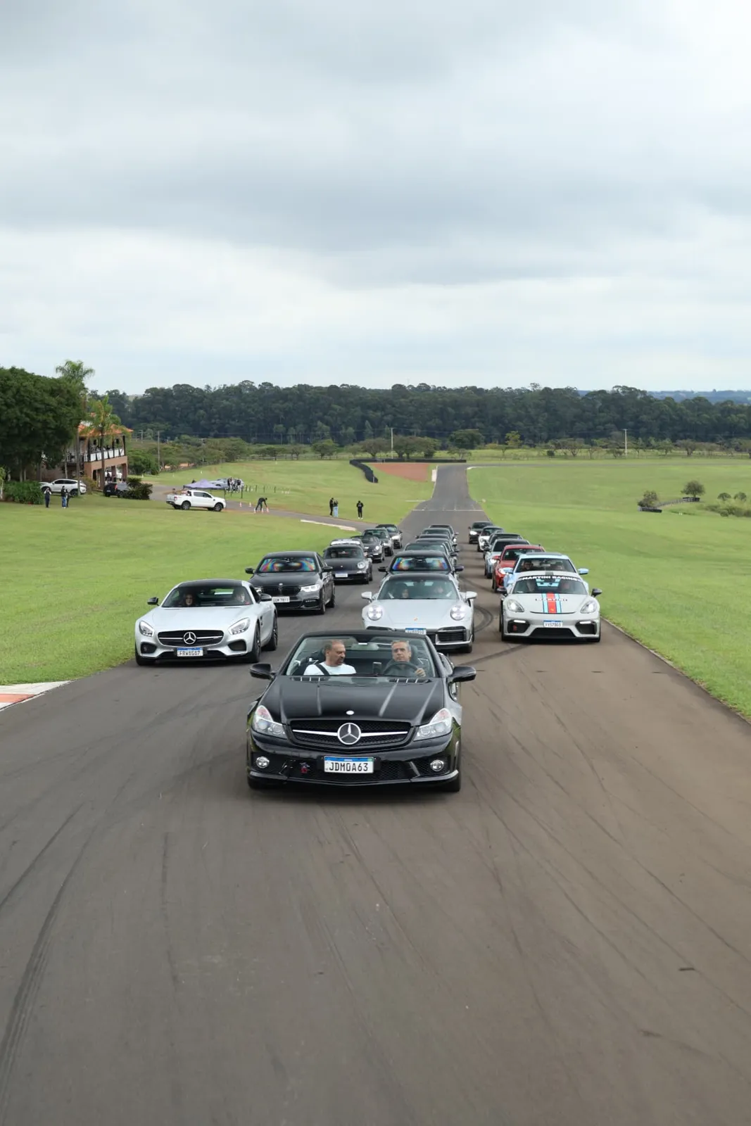 Mercedes SL 63 preta liderando o comboio na reta com a sede ao fundo