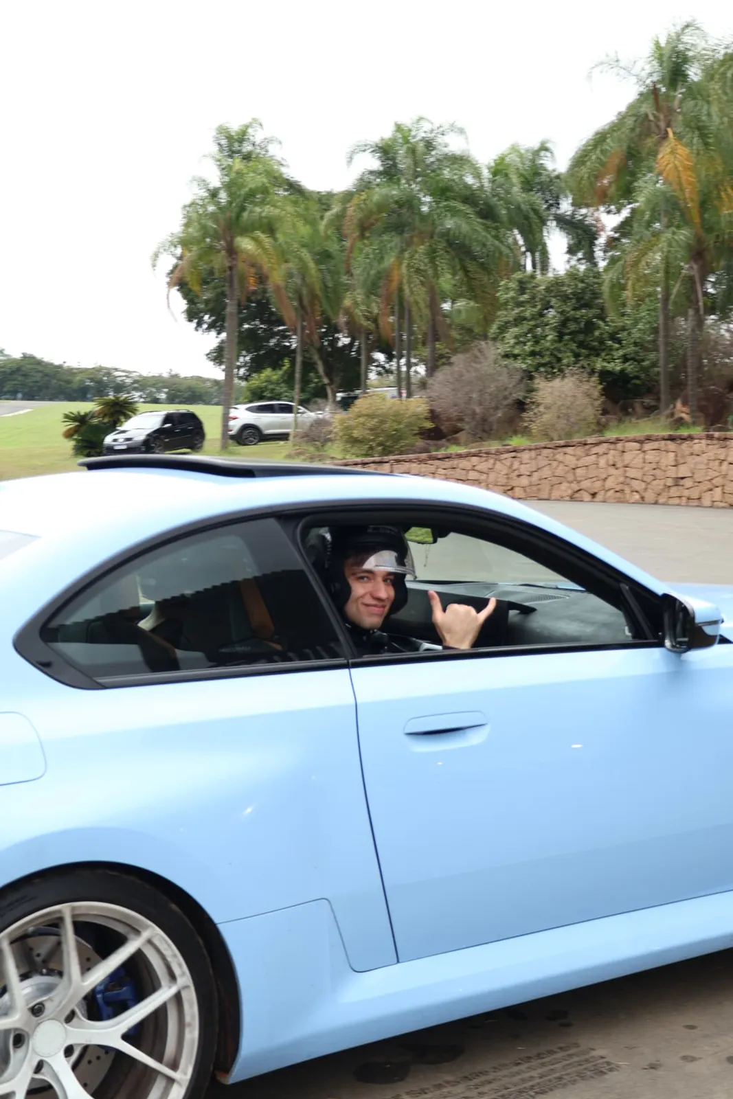 Piloto sorridente acenando de dentro do BMW M2 azul