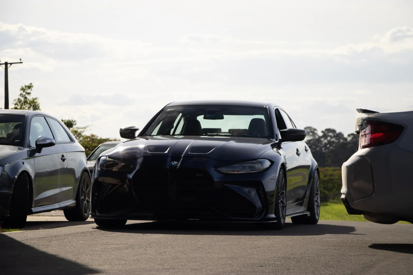 BMW M3 preto de frente no paddock