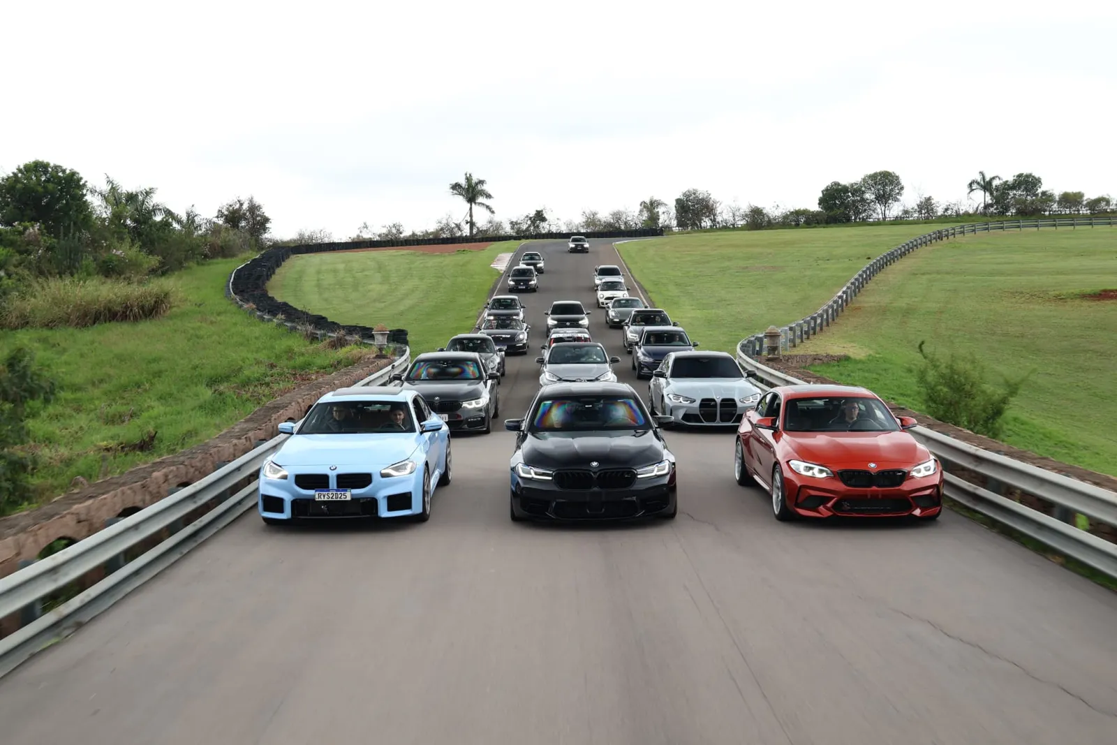 Trio BMW M2 azul, M5 e M2 Competition à frente do comboio na ponte