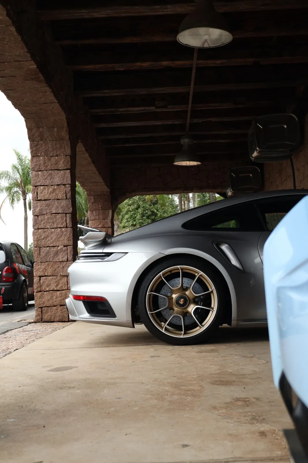 Porsche 911 Turbo S com rodas douradas sob os arcos de pedra