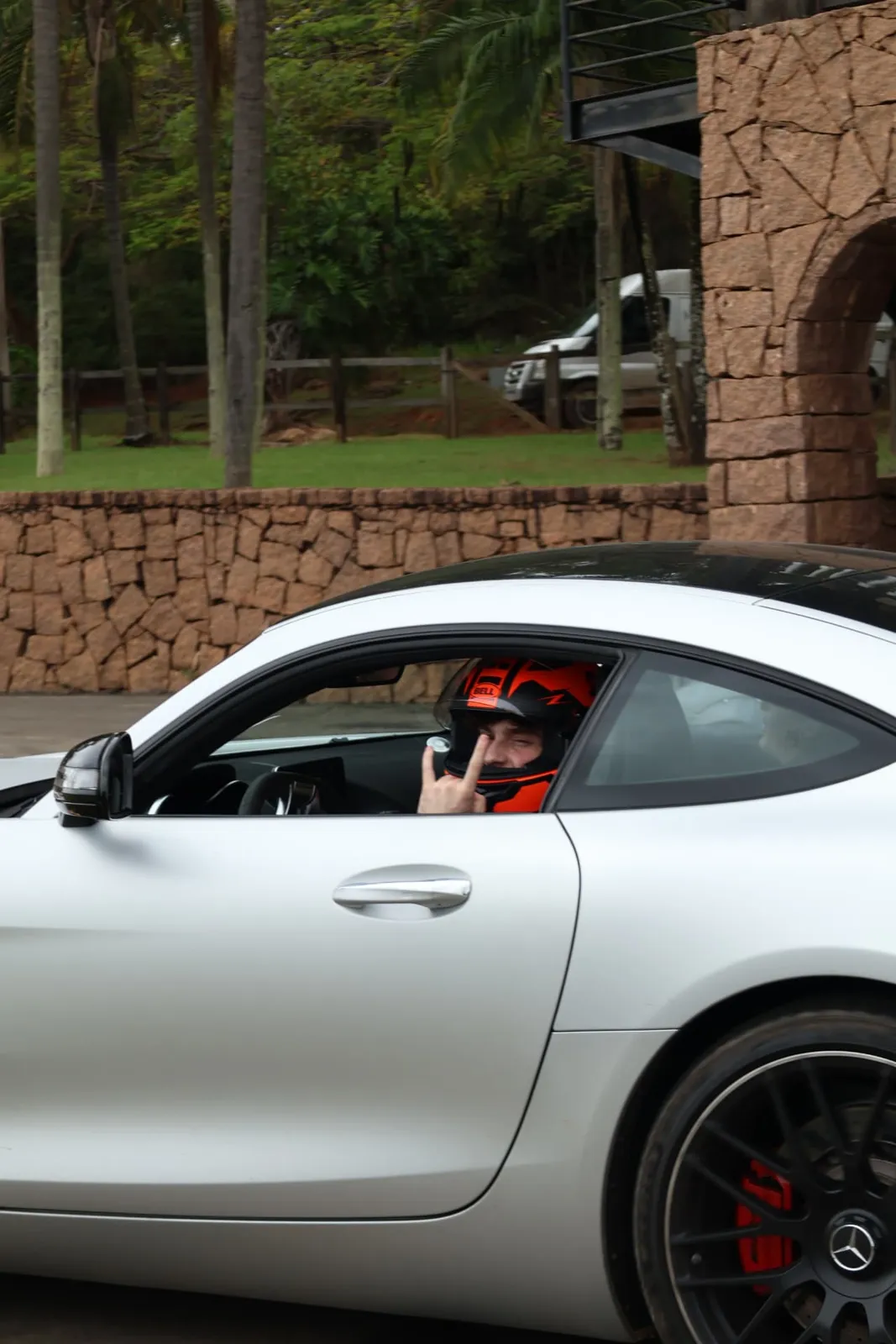 Piloto de capacete fazendo sinal de rock no Mercedes-AMG GT