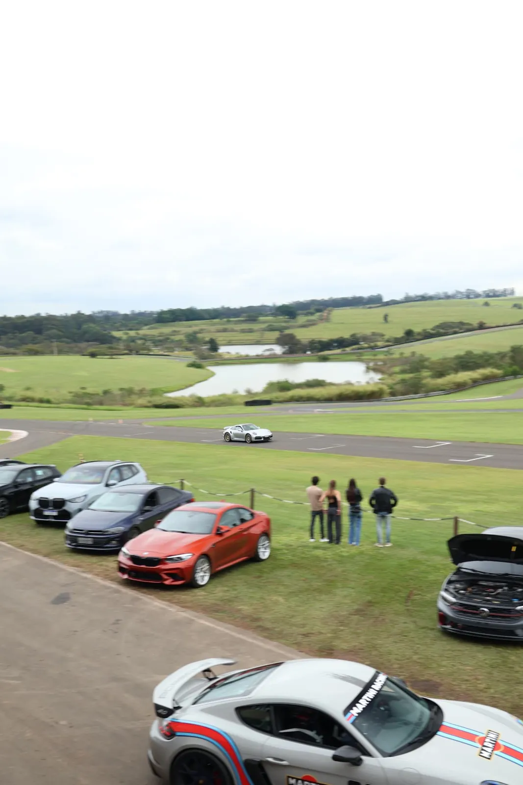 Público assistindo ao Porsche 911 Turbo S na pista com o lago ao fundo