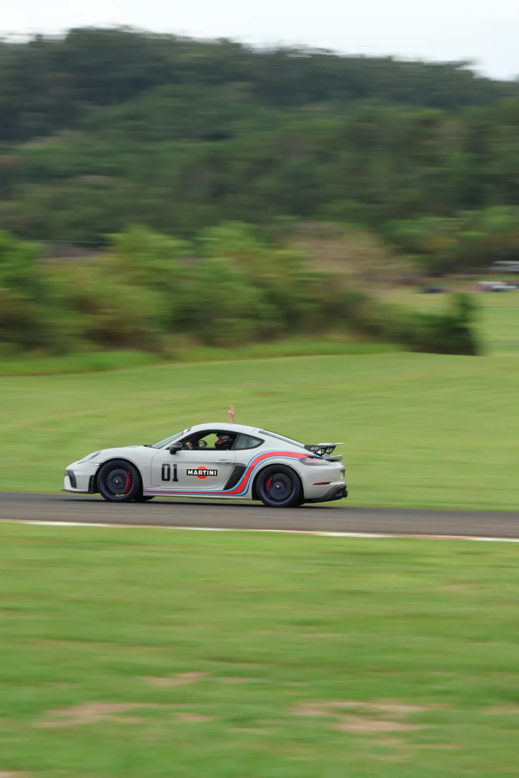 Piloto acenando do Porsche Cayman GT4 Martini em velocidade