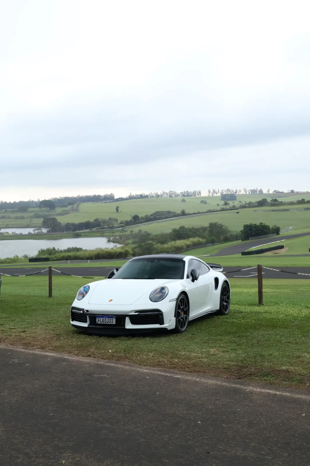 Porsche 911 Turbo S branco com o lago e o autódromo ao fundo
